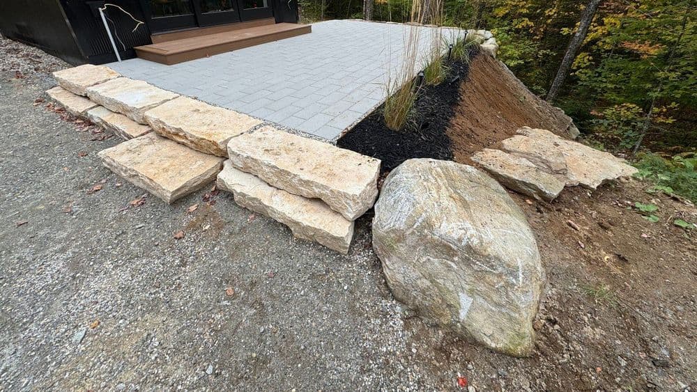 Natural stone landscaping with pavers, gravel, and plants near a modern home exterior.